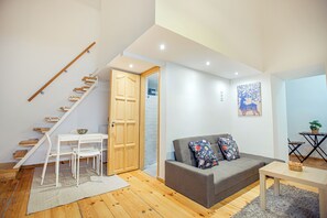 A modern living room with a staircase, grey sofa, and wooden flooring. - Cute gallery flat in Budapest Pearl  (Budapest)