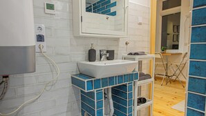 A bathroom with a white sink, blue-tiled vanity, and a mirror above it. - Cute gallery flat in Budapest Pearl  (Budapest)