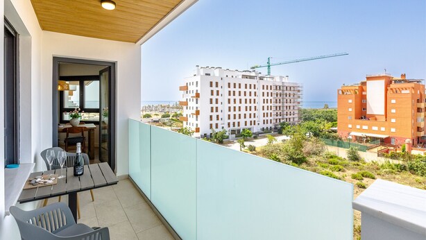 Un balcon avec une table dressée pour deux personnes, donnant sur un chantier de construction et un immeuble en construction.