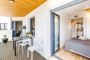 Ein modernes Interieur mit Essbereich, einem Bett und einer Schiebeglastür, die auf einen Balkon führt.