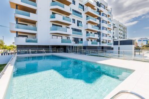 Ein modernes Gebäude mit mehreren Balkonen und einem Schwimmbad.