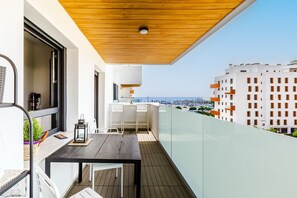 Ein Balkon mit Holzboden, einem Tisch, Stühlen und Blick auf eine Stadtansicht.