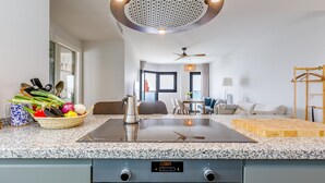 Une cuisine moderne dotée d’un plan de travail en granit, d’une cuisinière encastrée et d’une horloge numérique.