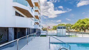 Un bâtiment moderne doté d’une piscine, d’un espace extérieur aménagé et offrant une vue sur un ciel dégagé.