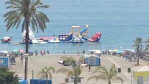 Ein Strand mit Palmen, einem Spielplatz und Sonnenschirmen.