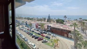 Ein Parkplatz mit mehreren Autos und im Hintergrund Blick auf Strand und Meer.