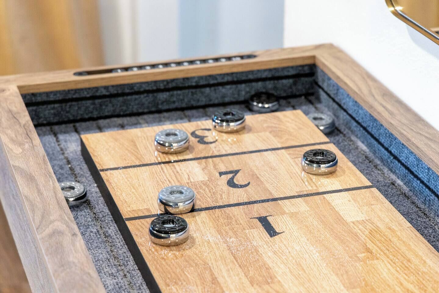 Taula de shuffleboard amb zones de puntuació numerades.