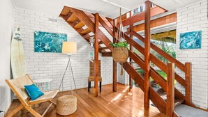 Un interior moderno con una escalera de madera, paredes de ladrillo blanco y obras de arte.