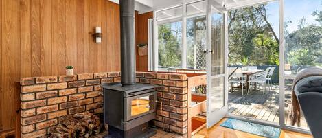 Ein modernes Interieur mit Kaminofen, einer Holzwand und einer Glastür zu einer Terrasse.