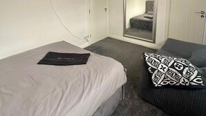 Une chambre avec un lit, une chaise, un néon en forme de cœur, une télévision et une armoire.