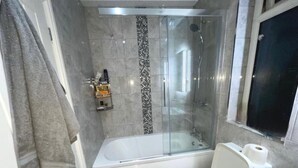 Une salle de bain avec une douche à parois de verre, une baignoire, des toilettes et un porte-serviettes.