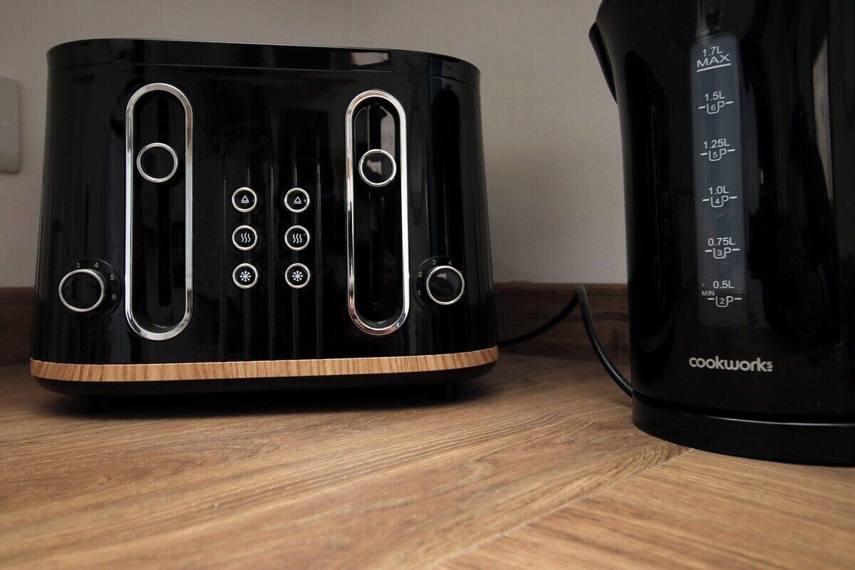 Ein schwarzer Wasserkocher mit digitaler Anzeige und ein schwarzes Toastergerät mit Holzsockel.