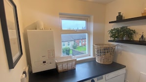A laundry room with a washing machine, dryer, and a window with a view of houses.