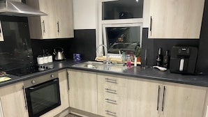 A modern kitchen with a black stove, stainless steel sink, and wooden cabinets.