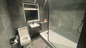 A modern bathroom with a toilet, sink, and shower.