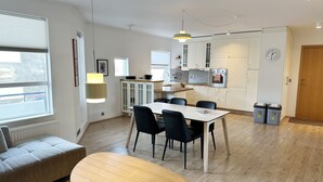 Eine moderne Küche mit weißen Schränken, einem Essbereich mit Tisch und Stühlen sowie einem roten Teppich.