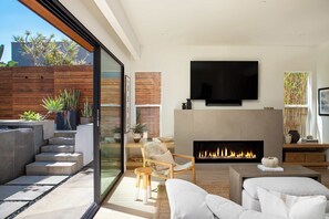 Una sala de estar moderna con chimenea, asientos confortables, un televisor de pantalla plana y vistas al exterior.