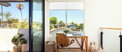 A modern office space with a large window, a wooden desk, a swivel chair, and decorative vases.