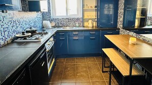 A compact kitchen with dark blue cabinets, a tiled backsplash, and a window above the sink. - Immaculate 3-bed Apartment in London (London)