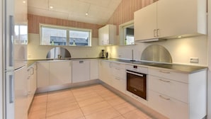 A modern kitchen with white cabinets, a stainless steel range hood, and a built-in oven. - 2 Houses In One I Family Friendly I Kids I Sauna I Beach I Large Garden (Haderslev)