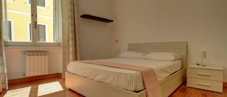 A bedroom with a bed, bedside table, and a window with curtains.