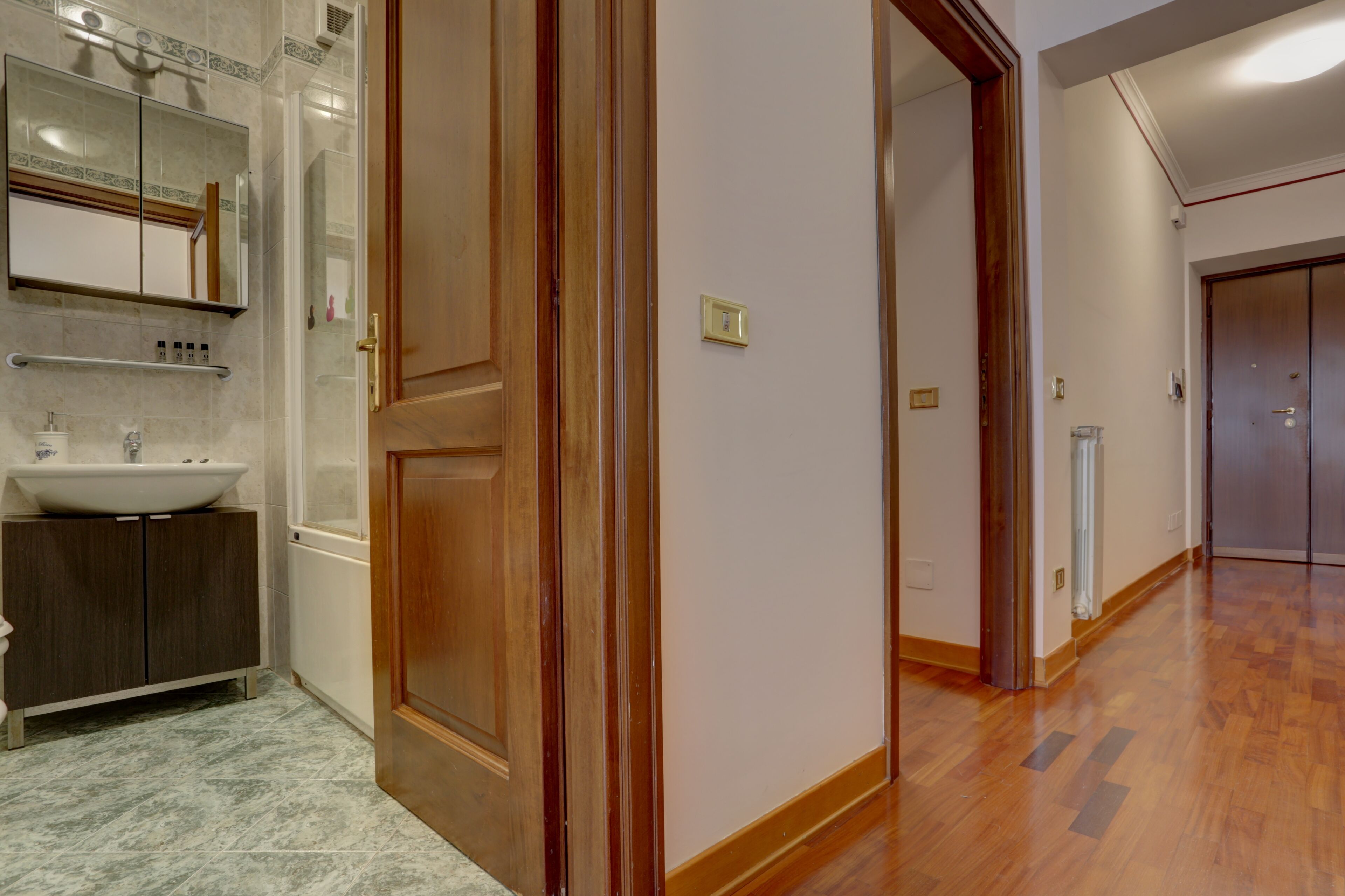 A hotel room with a wooden door, a white sink, and a mirror above it.