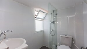 Un baño moderno con ducha de vidrio, lavamanos e inodoro.
