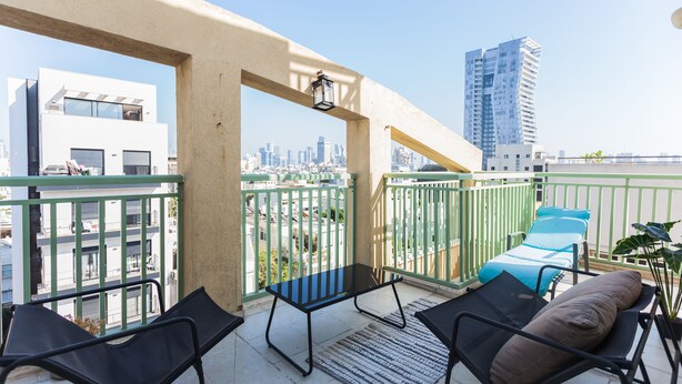 Un balcón con dos sillones de descanso, una mesita y vistas a un paisaje urbano.