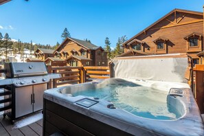 Une cabane en bois avec un jacuzzi et un barbecue Weber Genesis.