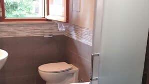 A small bathroom with two toilets, a sink, and a window. - Studio in a Poolside Residence (San Michele al Tagliamento)