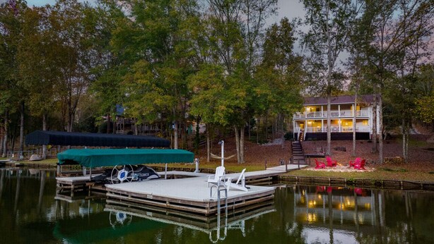Une jetée au bord du lac avec un bateau à quai, un bâtiment doté d’un balcon et une zone boisée.