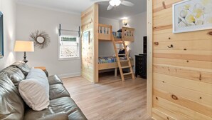 Ein Zimmer mit einem Etagenbett, einem Deckenventilator, einer Lampe, einer Holzwand und einem gerahmten Bild.