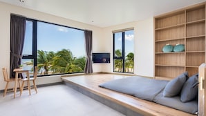 A modern bedroom with a large bed, a TV, and a view of palm trees. - The Rebirth Apartment Binh Chau Ho Tram (Ho Chi Minh City)