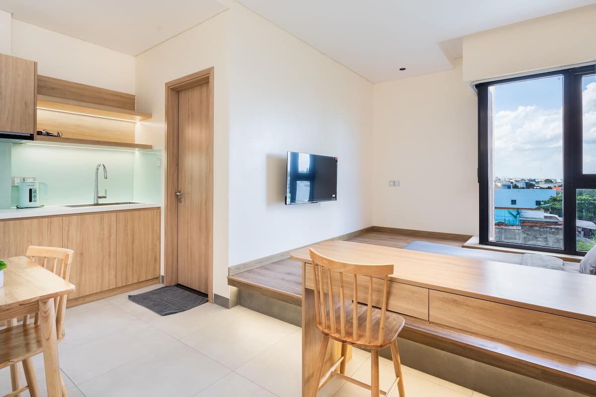 A modern kitchen with wooden cabinets, a built-in oven, and a large window with curtains.