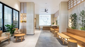A modern reception area with wooden furniture, a map projection on the wall, and potted plants. - The Rebirth Apartment Binh Chau Ho Tram (Ho Chi Minh City)