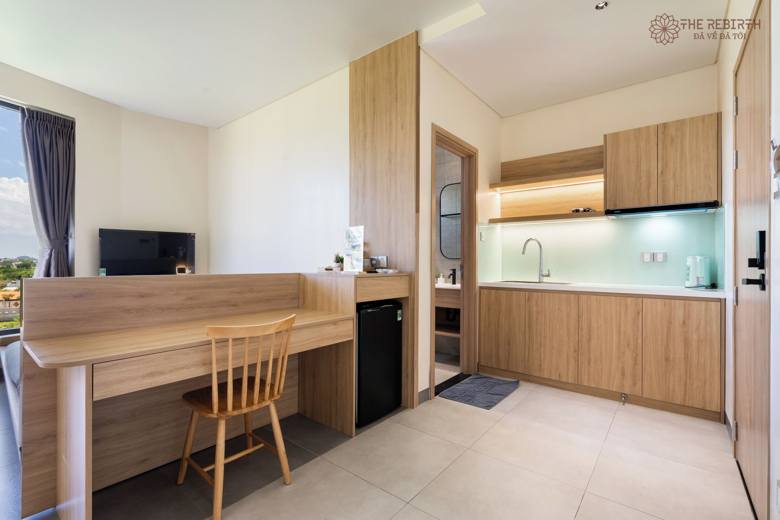 Una cocina moderna con armarios de madera, lavavajillas integrado y un pequeño comedor con una silla.
