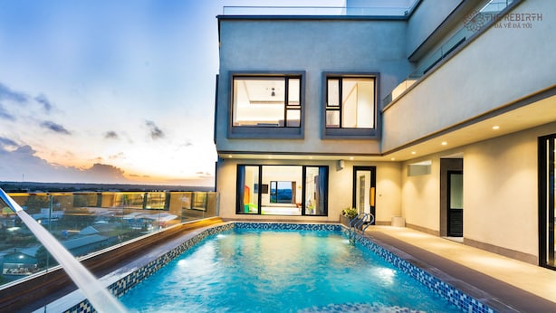 A modern building with a rooftop pool, large windows, and a view of the sunset. - The Rebirth Apartment Binh Chau Ho Tram (Ho Chi Minh City)