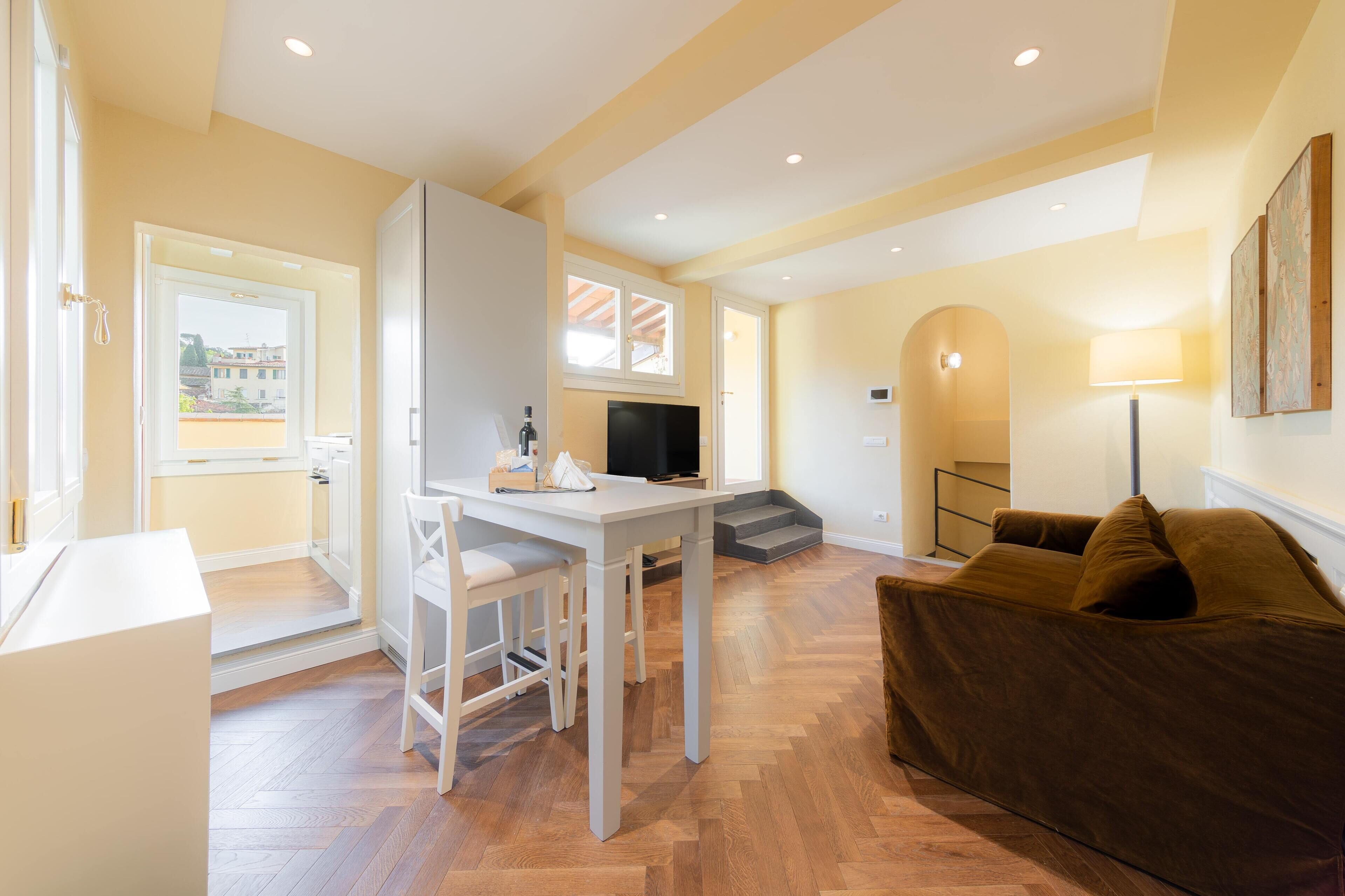 Una sala de estar moderna con sofá, televisión y un comedor con mesa y sillas.