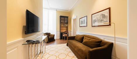Un salon moderne avec un canapé marron, un téléviseur à écran plat, une table basse en verre et un tapis à motifs.