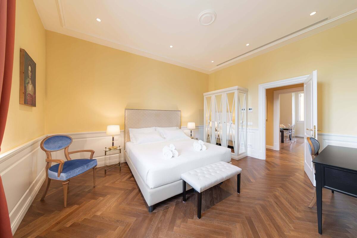 Habitació d'hotel amb un llit gran, una cadira de fusta, una panxa i un escriptori.