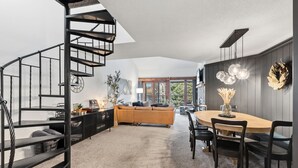 Un intérieur moderne avec un escalier en colimaçon, un coin repas et un canapé.