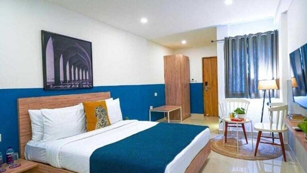 Een hotelkamer met een bed, een bureau, een stoel en een schilderij aan de muur.