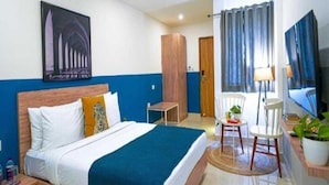Een hotelkamer met een bed, bureau, stoel, televisie en deur.