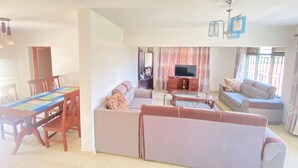 Un salón amplio con un conjunto de sofás, un televisor y una mesa de comedor con sillas.
