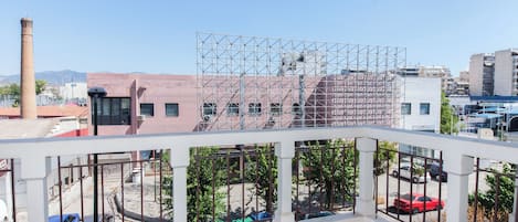 A balcony with a metal railing overlooking a parking area and buildings.