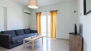 A living room with a sofa, a coffee table, a TV on a stand, and a window with curtains. - Modern Equipped apt w Balcony GC 3120-02 (Athens)