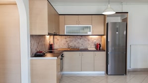 A modern kitchen with light wood cabinets, a stainless steel refrigerator, a microwave, and a tiled backsplash. - Modern Equipped apt w Balcony GC 3120-02 (Athens)