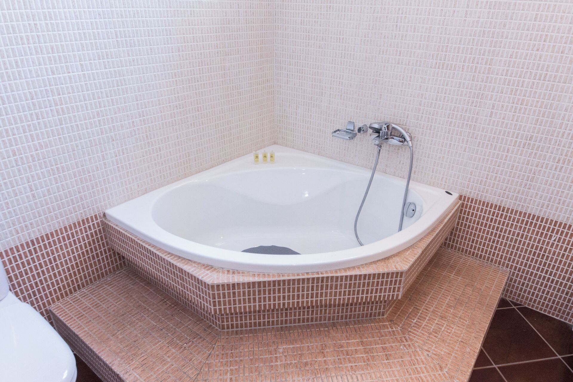 A bathroom with a freestanding bathtub, a toilet, and tiled walls.