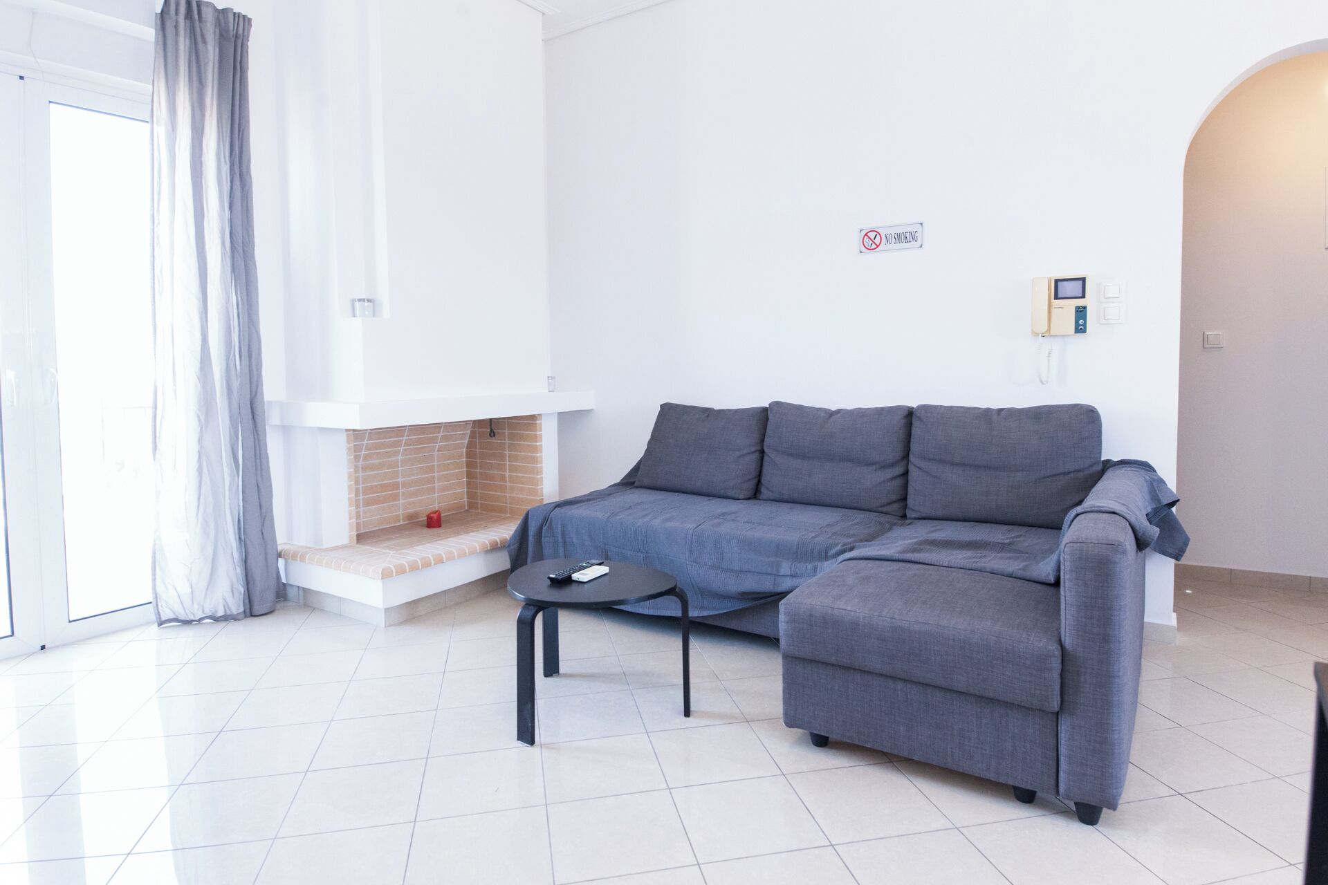 A modern living room with a grey sofa, a small black table, and a fireplace.