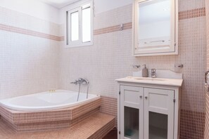 A bathroom with a bathtub, a sink, and a mirror.